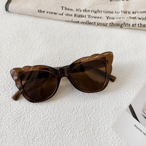 Close-up of dark brown cat-eye sunglasses with detailed frame specs on inner temple