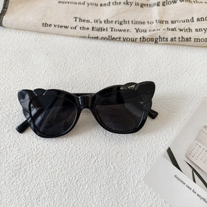 Close-up of black cat-eye sunglasses with unique scalloped wavy texture on the frame