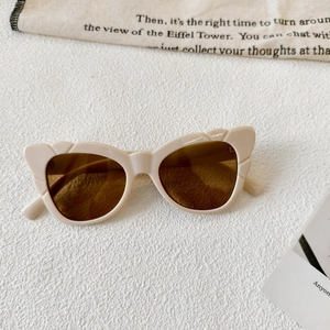 Detail of trendy butterfly cat-eye sunglasses with cream frames and wavy edges