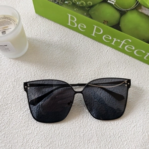Detail of black oversized square sunglasses with silver rivets on a minimalist background