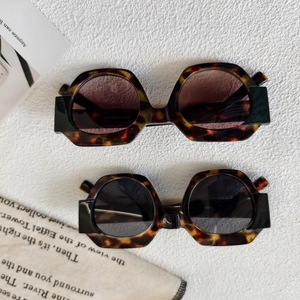 Fashionable round geometric tortoiseshell sunglasses with dark lenses on fabric background
