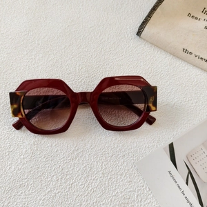Detailed close-up of burgundy hexagonal sunglasses with gradient lenses and tortoise accents