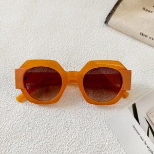 Detail view of orange geometric sunglasses with thick hexagonal frames and gradient lenses