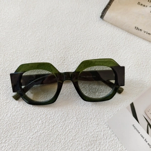 Detail of round two-tone sunglasses with green and black frames on textured fabric