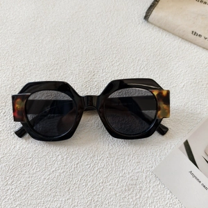 Detail of geometric black sunglasses with tortoiseshell accents on the temple hinges