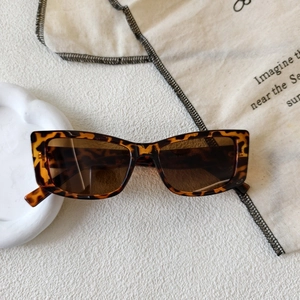 Retro square tortoiseshell sunglasses with dark lenses on a decorative white tray