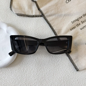 Detail view of black rectangular sunglasses with size markings on white textured surface
