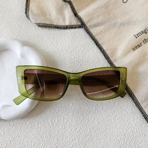 Detail of square green translucent sunglasses with brown gradient lenses on a tray
