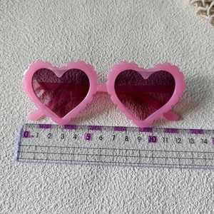 Detailweergave van roze hartvormige zonnebril met golfpatroon en 14 cm breedte maat