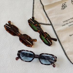 Three pairs of oval polygon sunglasses in tortoiseshell and marble frames on a white surface