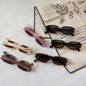 Five pairs of vintage small frame sunglasses in multiple colors on a textured white surface