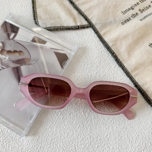 Detail of pink translucent irregular oval sunglasses with brown gradient lenses