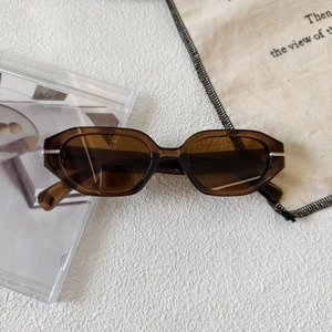Detailed close-up of amber textured small frame sunglasses with silver metal hinge accents
