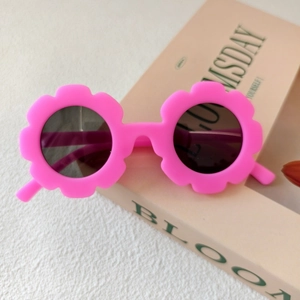 Dettaglio degli occhiali da sole rosa a forma di fiore per bambini su un libro vintage