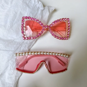 Détail de lunettes de soleil œil-de-chat à strass roses et monture bouclier à perles