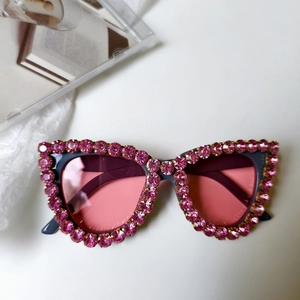 Détail de lunettes de soleil œil-de-chat avec strass roses et verres dégradés roses