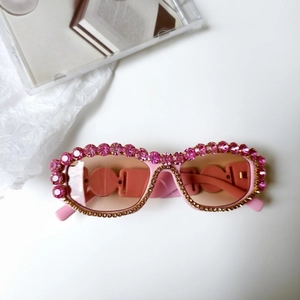 Détail de lunettes de soleil roses avec strass surdimensionnés et chaîne dorée