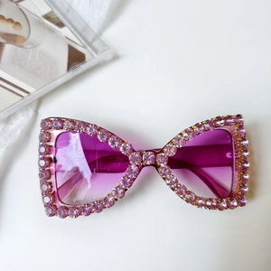 Détail de lunettes de soleil nœud rose avec strass brillants et verres dégradés
