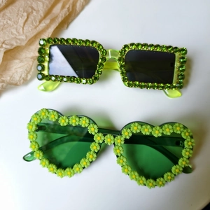 Detail view of neon green rectangular sunglasses with rhinestones and green heart daisy frames