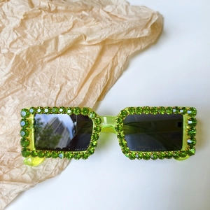 Macro shot of neon green translucent frames with rows of green rhinestones and dark lenses