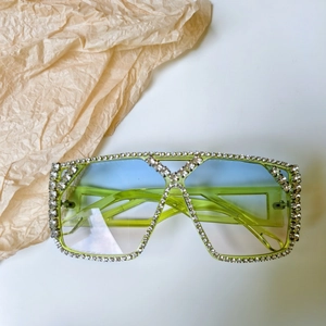 Macro detail of oversized green translucent sunglasses with sparkling rhinestone crystals