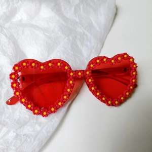 Detail of red heart-shaped bridal sunglasses adorned with red and yellow daisies