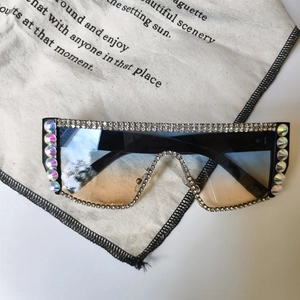 Dettaglio occhiali da sole oversize con lenti sfumate blu e montatura con strass