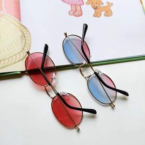Detail of vintage metal frame sunglasses with red and gradient lenses on a white surface