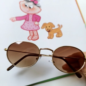 Detailed close-up of retro oval metal frame sunglasses with textured bridge and amber lenses