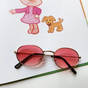 Macro view of gold metal frame with engraved nose bridge on oval pink sunglasses