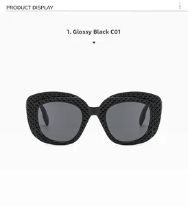 Detail of bright black oval sunglasses with geometric diamond-textured frame and grey lenses