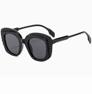 Close-up of black oval sunglasses with refined diamond lattice texture on frames
