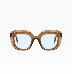 Detail of light brown oval sunglasses with textured diamond-cut frame and blue lenses