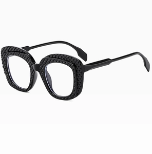 Close-up of black oval sunglasses featuring a textured geometric frame and clear lenses