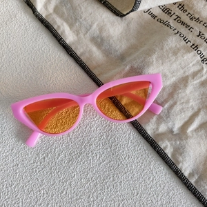 Detail of cat eye sunglasses with a pink glossy frame and translucent orange lenses