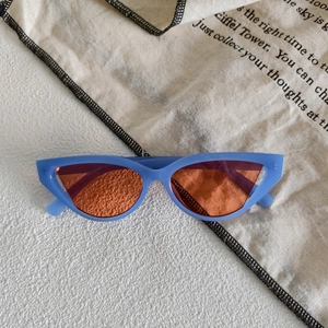 Detail shot of light blue cat-eye sunglasses with tinted red-orange lenses and modern frame