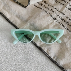 Detail view of mint green retro cat eye sunglasses on a vintage patterned textile