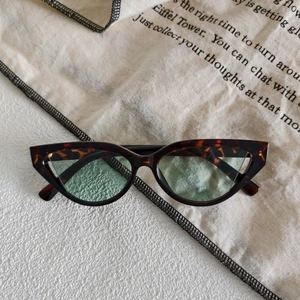 Detailed view of tortoiseshell cat-eye sunglasses on artistic textured fabric background