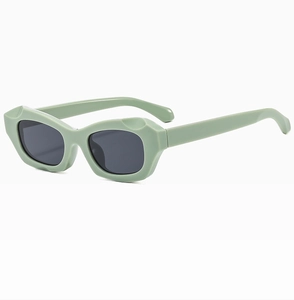 Détail de lunettes de soleil rectangulaires vertes avec monture épaisse et coupe géométrique