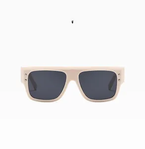 Detailed macro view of beige square sunglasses with silver rivet accents and grey lenses
