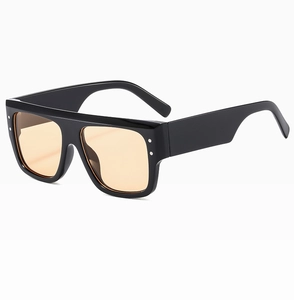 Detail of square oversized sunglasses featuring thick black frames and tinted orange lenses