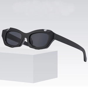 Lunettes de soleil œil de chat à monture épaisse noire sur un socle blanc minimaliste