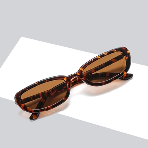 Classic tortoiseshell oval sunglasses with brown lenses on a modern geometric background