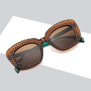 Chic amber oval sunglasses with textured frames and brown lenses in a minimalist studio shot