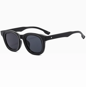 Close-up of retro black round frame sunglasses with metal rivets on white background
