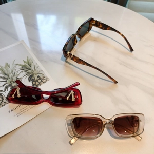 Detailed flat lay of rectangular sunglasses with golden V-shaped logo on temples
