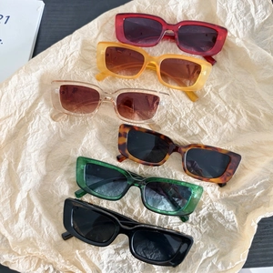 Flat lay of retro rectangle sunglasses in various colors on beige textured background