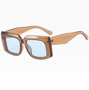 Macro view of chunky square translucent brown sunglasses frame with blue lenses and metal detail