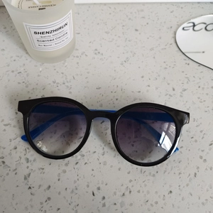 Détail de lunettes de soleil rondes pour enfants, monture noire et branches bleues