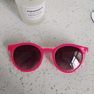 Gros plan de lunettes de soleil rondes rouge rose avec verres sur fond de pierre